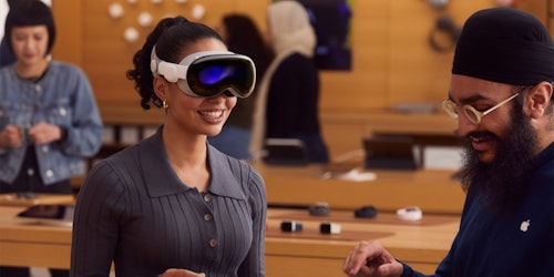 A customer being fitted for a Vision Pro headset by an Apple employee at an Apple store