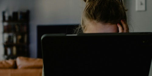 A woman with her head in her hands sits behind an ipad 