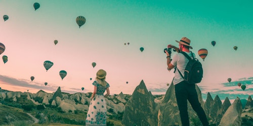 Two travel influencers amid a field of hot-air balloons