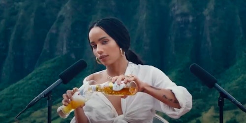 Zoe Kravitz pours a Michelob beer into a glass in front of two microphones in a still from a Super Bowl ad for the beer