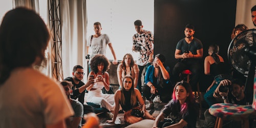 People sat on the floor listening to a woman talking at the front