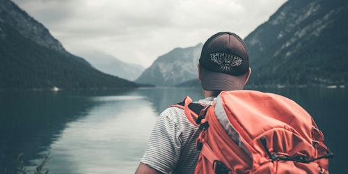 A man with a backpack looking out over a lake