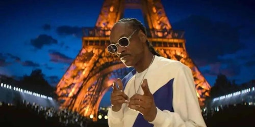 Snoop Dogg holdign a microphone and giving the peace sign with his fingers