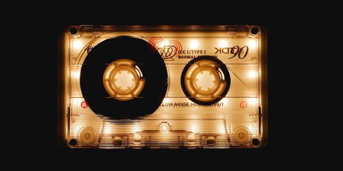 A casette tape is illuminated against a black background