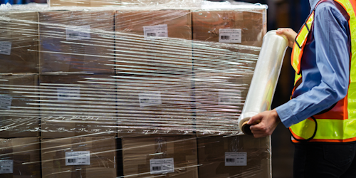 Boxes being wrapped in saran wrap for shipping in a factory