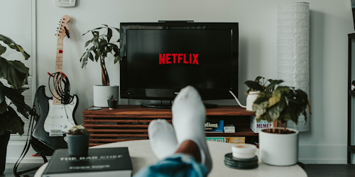 Netflix on TV screen with man's feet in foreground