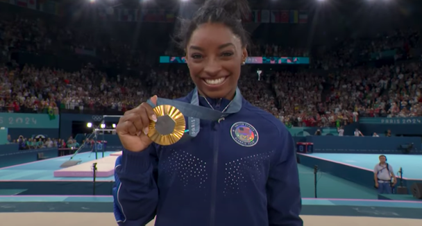 Simone Biles holds up a gold medal at the 2024 Paris Olympics