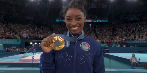 Simone Biles holds up a gold medal at the 2024 Paris Olympics