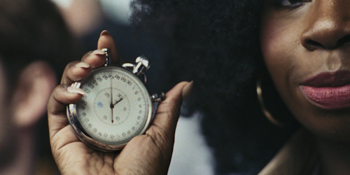 ‘Time’ is portrayed as a spectator holding a ticking stopwatch up to sprinter Emmanuel Oyinbo-Coker